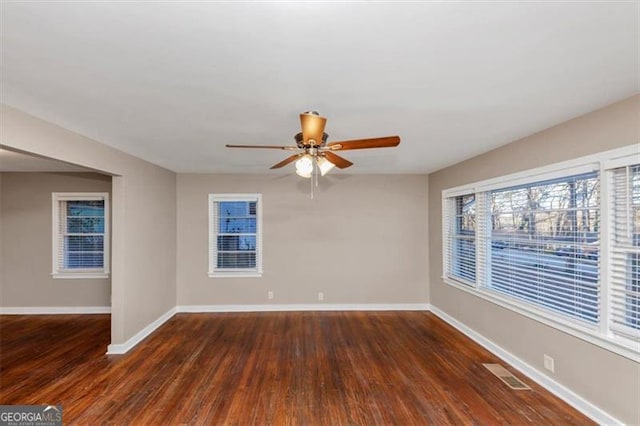 spare room featuring dark wood-style flooring, visible vents, ceiling fan, and baseboards