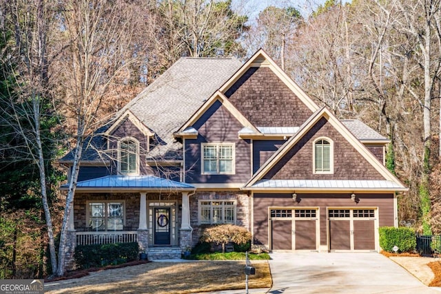 craftsman inspired home featuring metal roof, covered porch, a garage, concrete driveway, and a standing seam roof