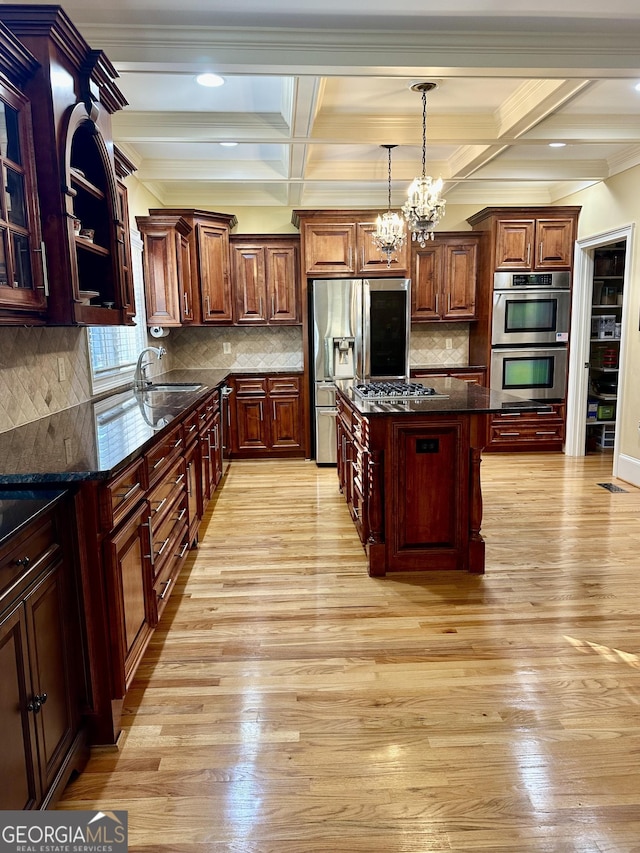 kitchen with light wood-type flooring, stainless steel appliances, beamed ceiling, and a center island