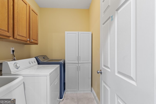 washroom featuring cabinet space, light tile patterned flooring, a sink, independent washer and dryer, and baseboards