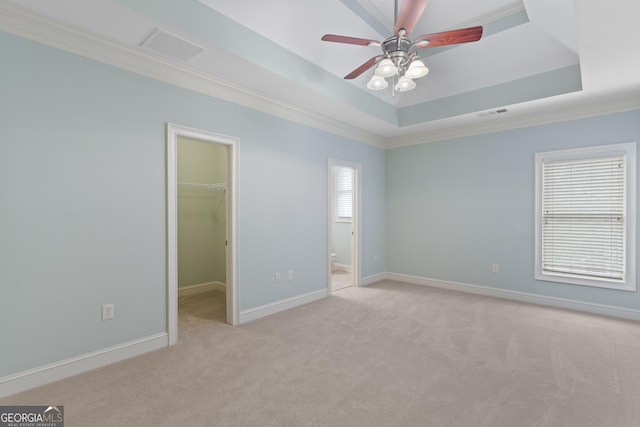 unfurnished bedroom featuring a walk in closet, baseboards, a raised ceiling, and carpet flooring