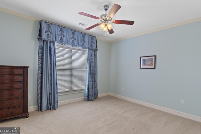 spare room featuring light carpet, a ceiling fan, baseboards, visible vents, and crown molding