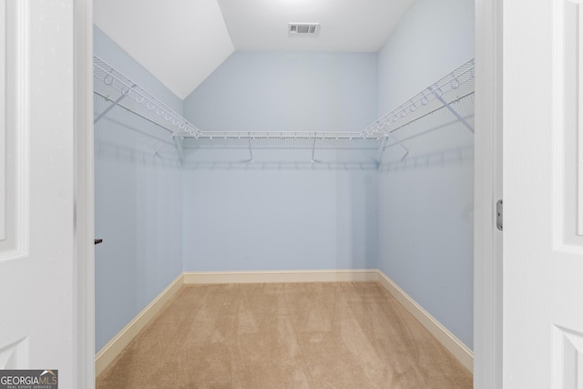 spacious closet featuring lofted ceiling, carpet flooring, and visible vents