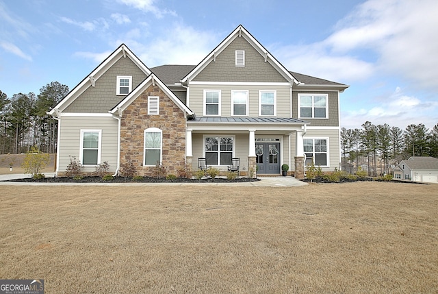 craftsman inspired home featuring a standing seam roof, stone siding, a front lawn, and french doors