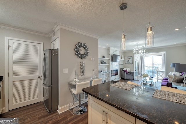 kitchen featuring white cabinetry, open floor plan, freestanding refrigerator, dark stone counters, and pendant lighting