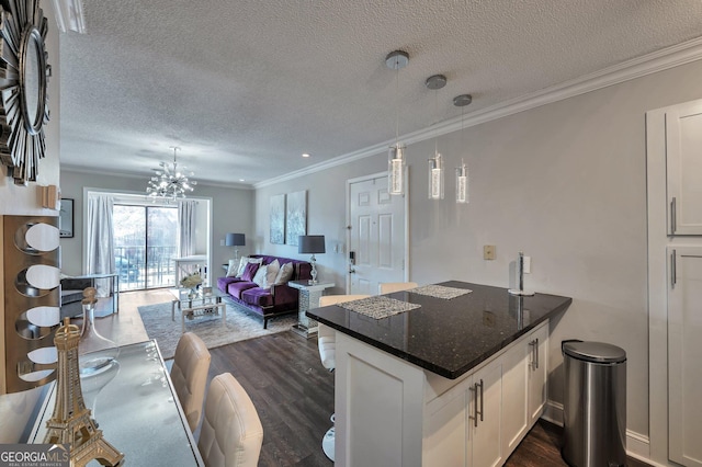 kitchen featuring a peninsula, white cabinets, open floor plan, dark stone counters, and pendant lighting