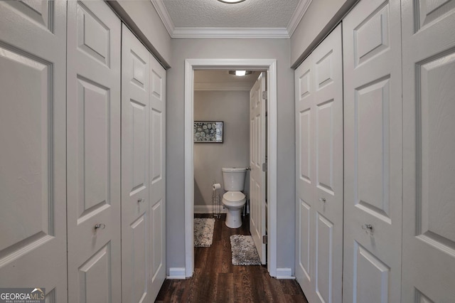 hallway with ornamental molding, dark wood-style flooring, a textured ceiling, and baseboards