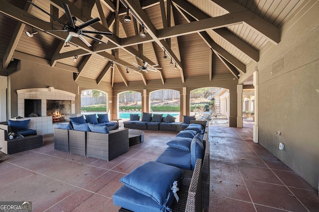 view of patio with a ceiling fan and an outdoor living space with a fireplace