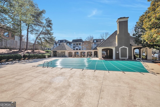 community pool with a patio and fence