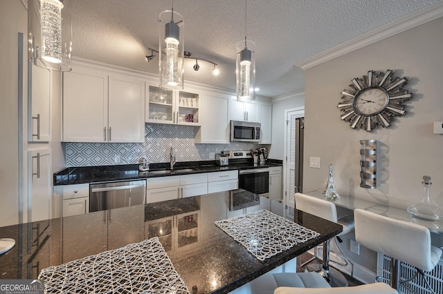 kitchen featuring appliances with stainless steel finishes, glass insert cabinets, white cabinets, a sink, and a kitchen bar