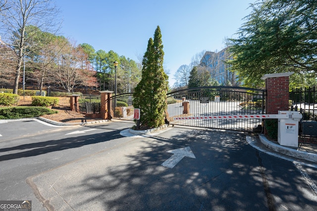 view of road featuring street lighting, a gate, curbs, and a gated entry