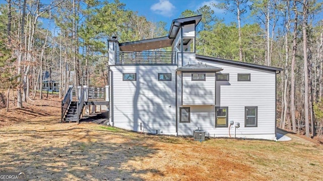 back of house with central air condition unit, stairs, and a yard