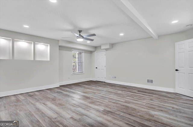 empty room with light wood-style flooring, beam ceiling, visible vents, and baseboards