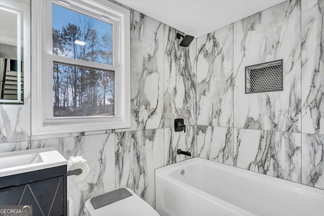 bathroom featuring toilet, vanity, washtub / shower combination, and tile walls