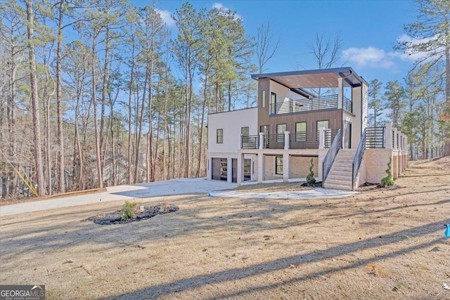 view of front of property with an attached garage, a balcony, stairs, and concrete driveway