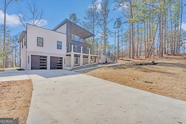 view of front of home with concrete driveway, a balcony, an attached garage, stairs, and stucco siding