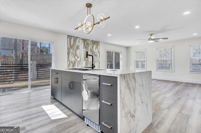 kitchen with light wood-style flooring, modern cabinets, gray cabinets, light countertops, and pendant lighting