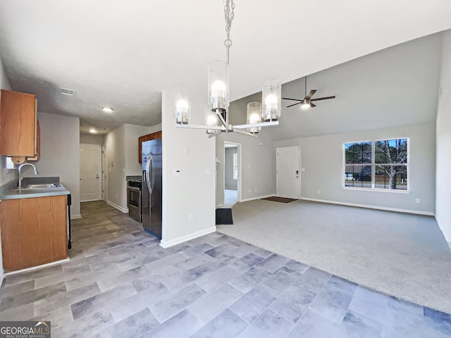 kitchen featuring light countertops, appliances with stainless steel finishes, open floor plan, light carpet, and a sink