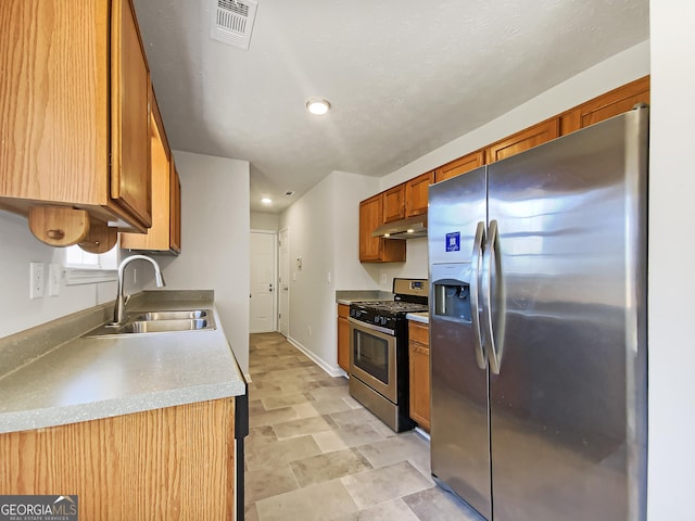 kitchen featuring stainless steel appliances, visible vents, light countertops, a sink, and under cabinet range hood