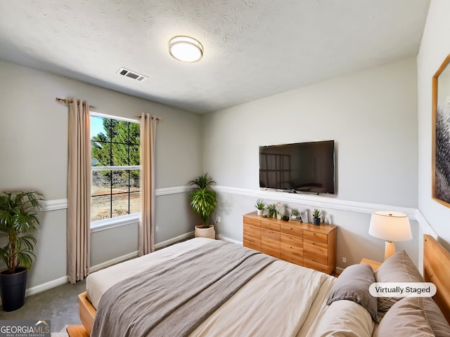 carpeted bedroom featuring a textured ceiling, visible vents, and baseboards