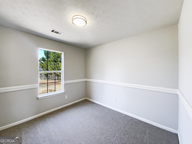 spare room featuring carpet flooring, visible vents, and baseboards