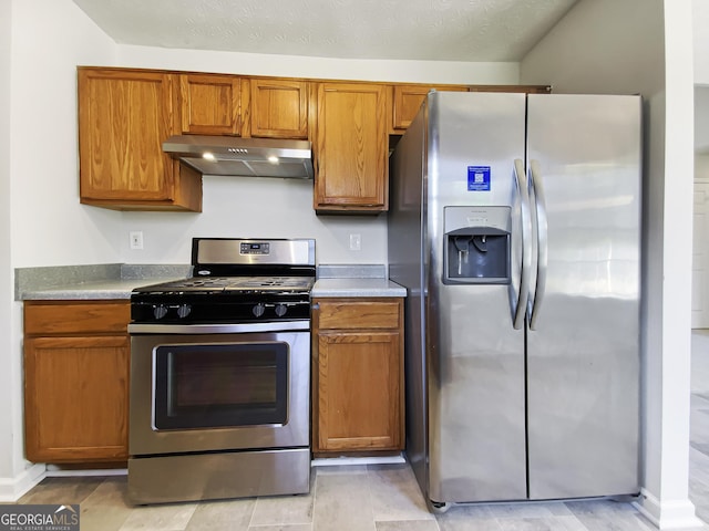 kitchen featuring light countertops, appliances with stainless steel finishes, brown cabinetry, and under cabinet range hood