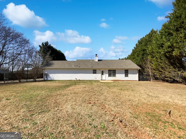 back of house with a chimney and a lawn