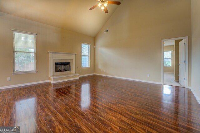 1186 Diamond Xing, Mcdonough, GA 30252 - unfurnished living room featuring dark wood-style floors, high vaulted ceiling, a fireplace, ceiling fan, and baseboards