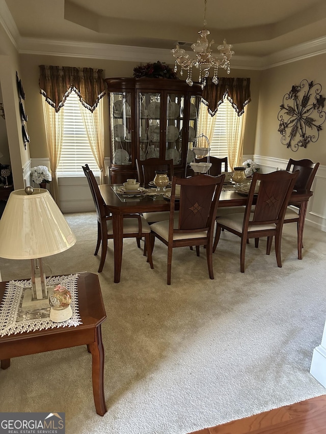 carpeted dining room with a healthy amount of sunlight, ornamental molding, and a raised ceiling