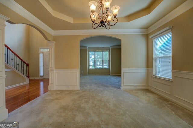 1186 Diamond Xing, Mcdonough, GA 30252 - unfurnished dining area with arched walkways, carpet floors, a tray ceiling, plenty of natural light, and a decorative wall