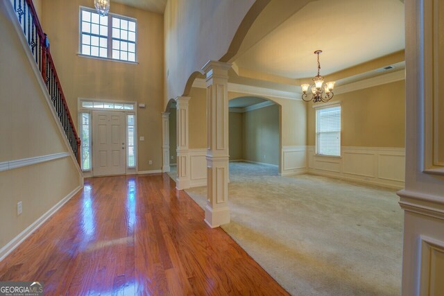 1186 Diamond Xing, Mcdonough, GA 30252 - entrance foyer with a chandelier, arched walkways, healthy amount of natural light, wood finished floors, and a wainscoted wall