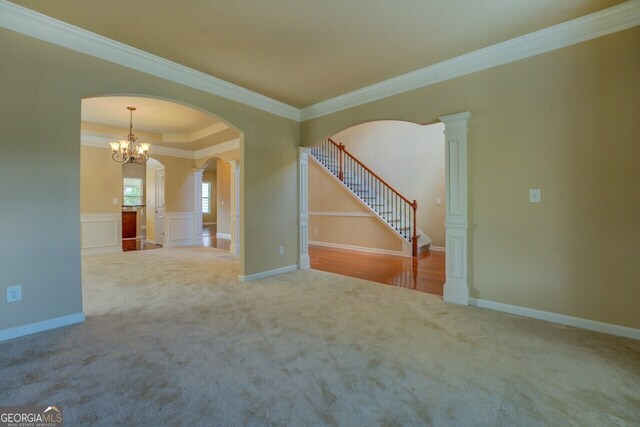 1186 Diamond Xing, Mcdonough, GA 30252 - carpeted empty room featuring ornamental molding, arched walkways, a chandelier, and stairs
