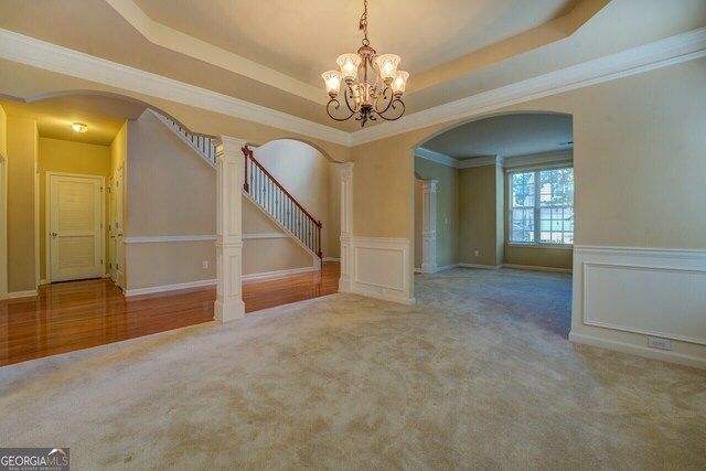 1186 Diamond Xing, Mcdonough, GA 30252 - carpeted spare room with arched walkways, stairs, a chandelier, a tray ceiling, and wainscoting