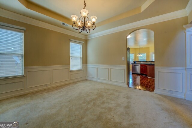1186 Diamond Xing, Mcdonough, GA 30252 - carpeted empty room featuring a chandelier, arched walkways, a decorative wall, wainscoting, and a raised ceiling