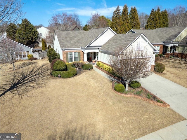 view of front facade featuring a shingled roof, concrete driveway, and brick siding