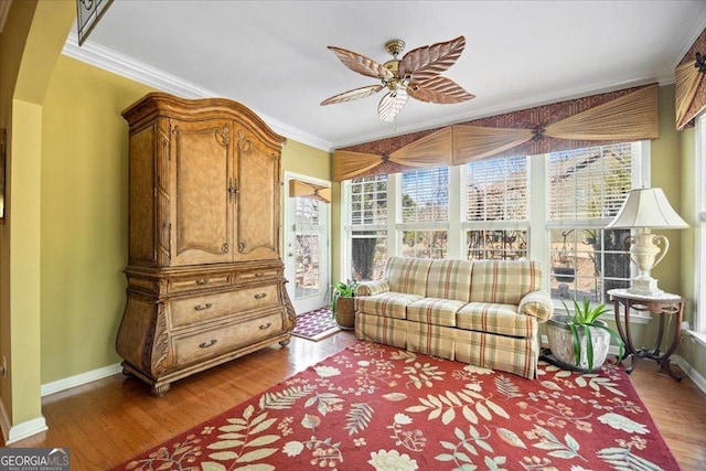 living area featuring baseboards, wood finished floors, and crown molding