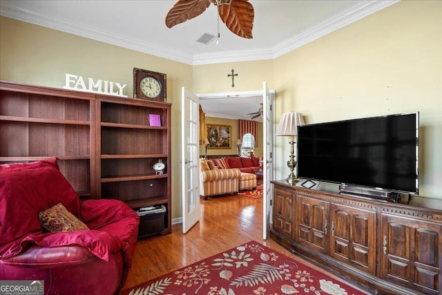 living area with ceiling fan, visible vents, crown molding, and wood finished floors