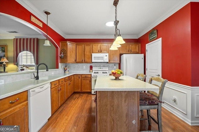 kitchen with white appliances, light countertops, a sink, and a kitchen bar