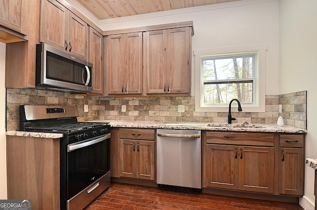 kitchen featuring stainless steel appliances, a sink, dark wood-style floors, and light stone countertops