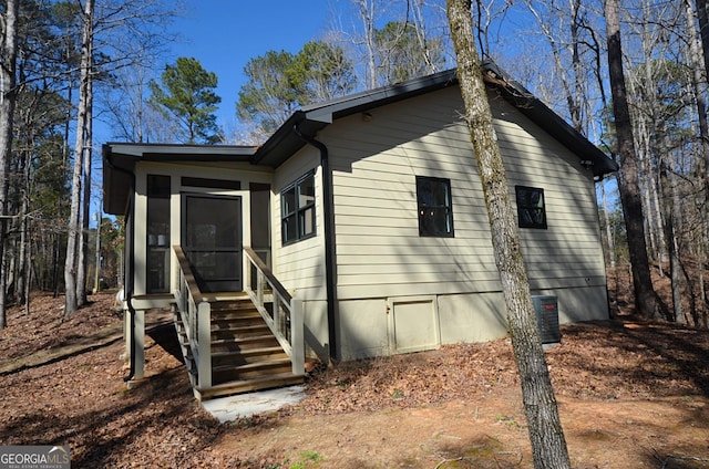 exterior space featuring entry steps, a sunroom, and central air condition unit