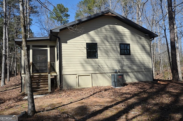 view of side of property with central air condition unit, a sunroom, and entry steps