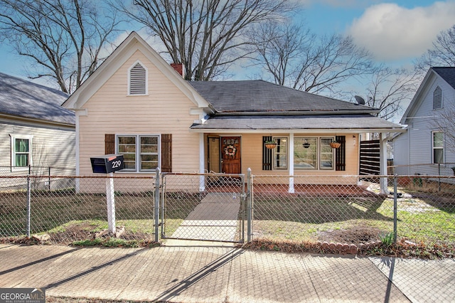 view of front of home featuring a fenced front yard, a front yard, a gate, and a chimney