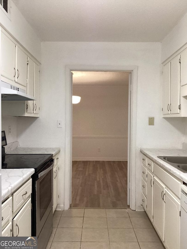 kitchen featuring stainless steel electric range oven, light countertops, under cabinet range hood, white cabinetry, and light tile patterned flooring