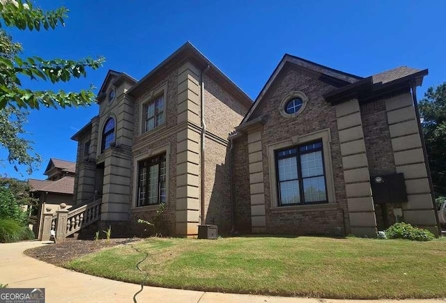 view of front of property featuring central air condition unit, a front lawn, and brick siding