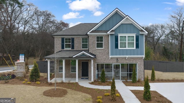 view of front of house with fence, a porch, board and batten siding, and brick siding