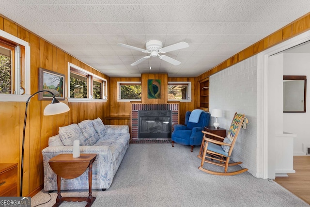 living room with a healthy amount of sunlight, wood walls, a brick fireplace, and visible vents