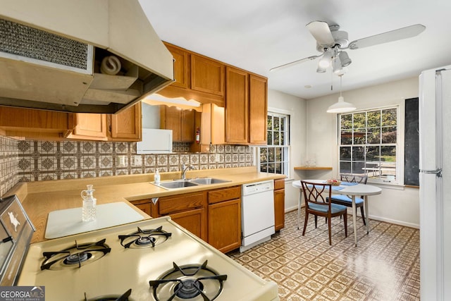 kitchen with white appliances, decorative backsplash, light countertops, under cabinet range hood, and a sink