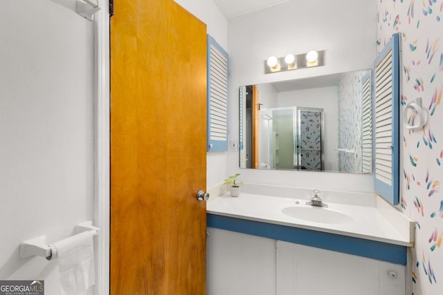 full bath featuring a shower stall, vanity, and wallpapered walls