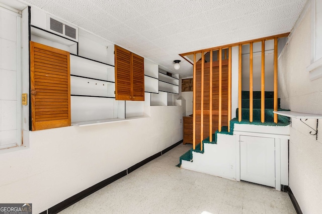 below grade area featuring baseboards, stairs, and visible vents