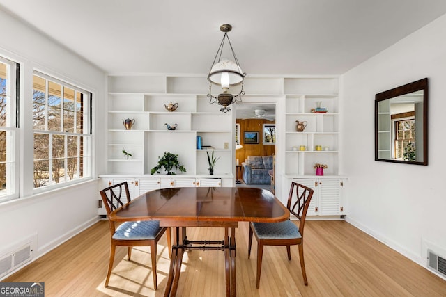 dining room featuring light wood finished floors, visible vents, and baseboards